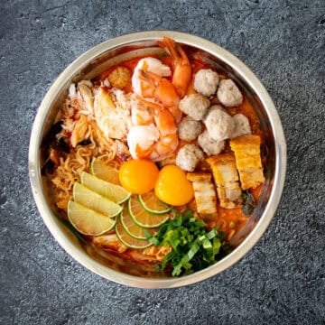 a bowl of mama tom yum noodles with various toppings.