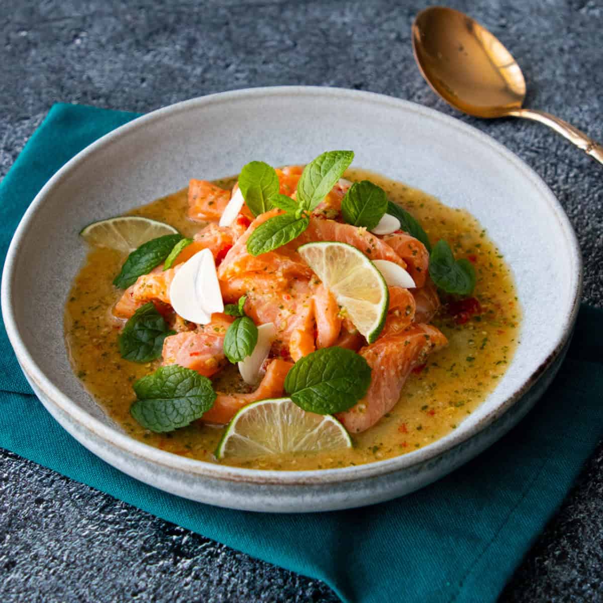 a plate of thai salmon salad with mint and lime slices garnish.