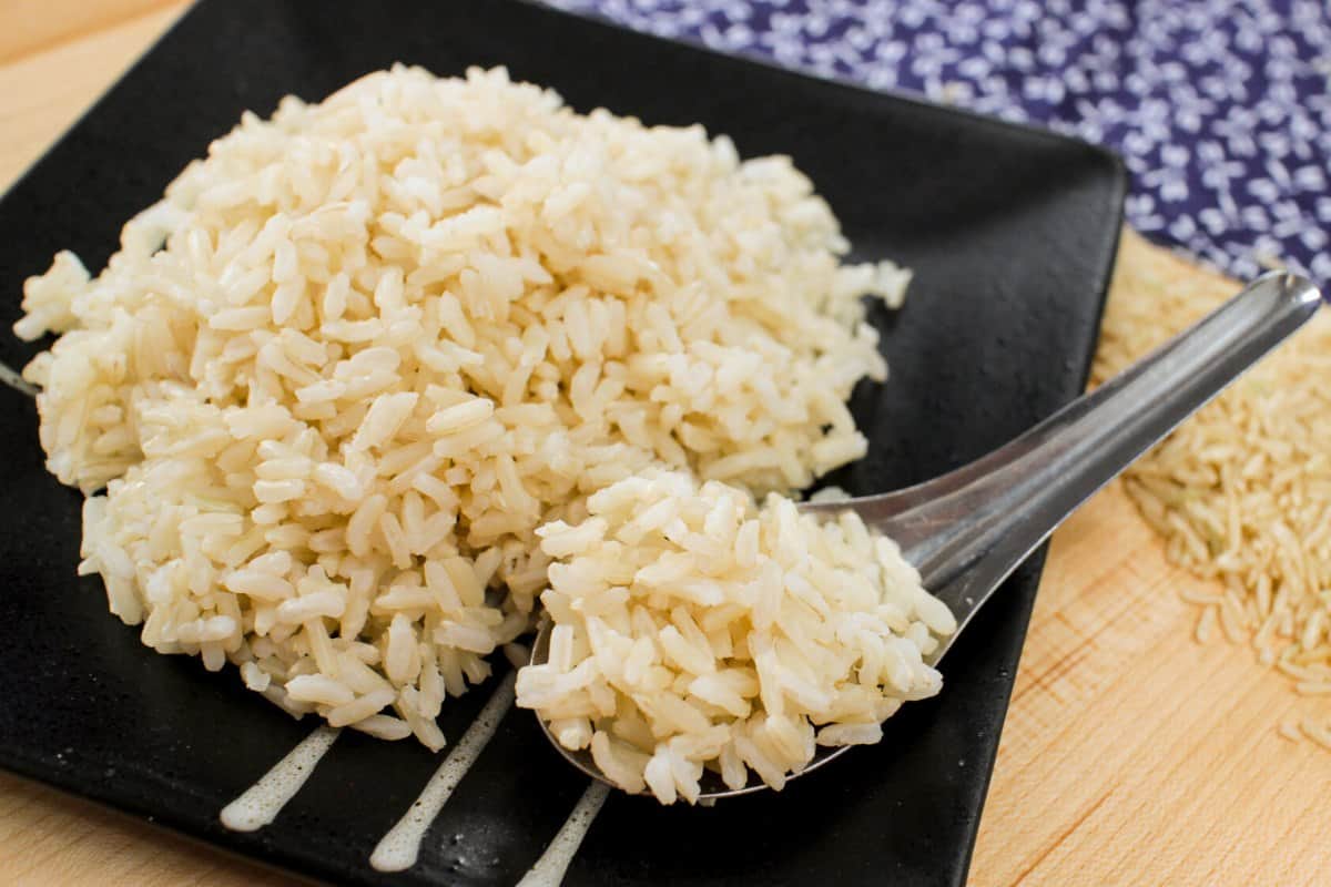 a plate of brown rice with rice on a spoon