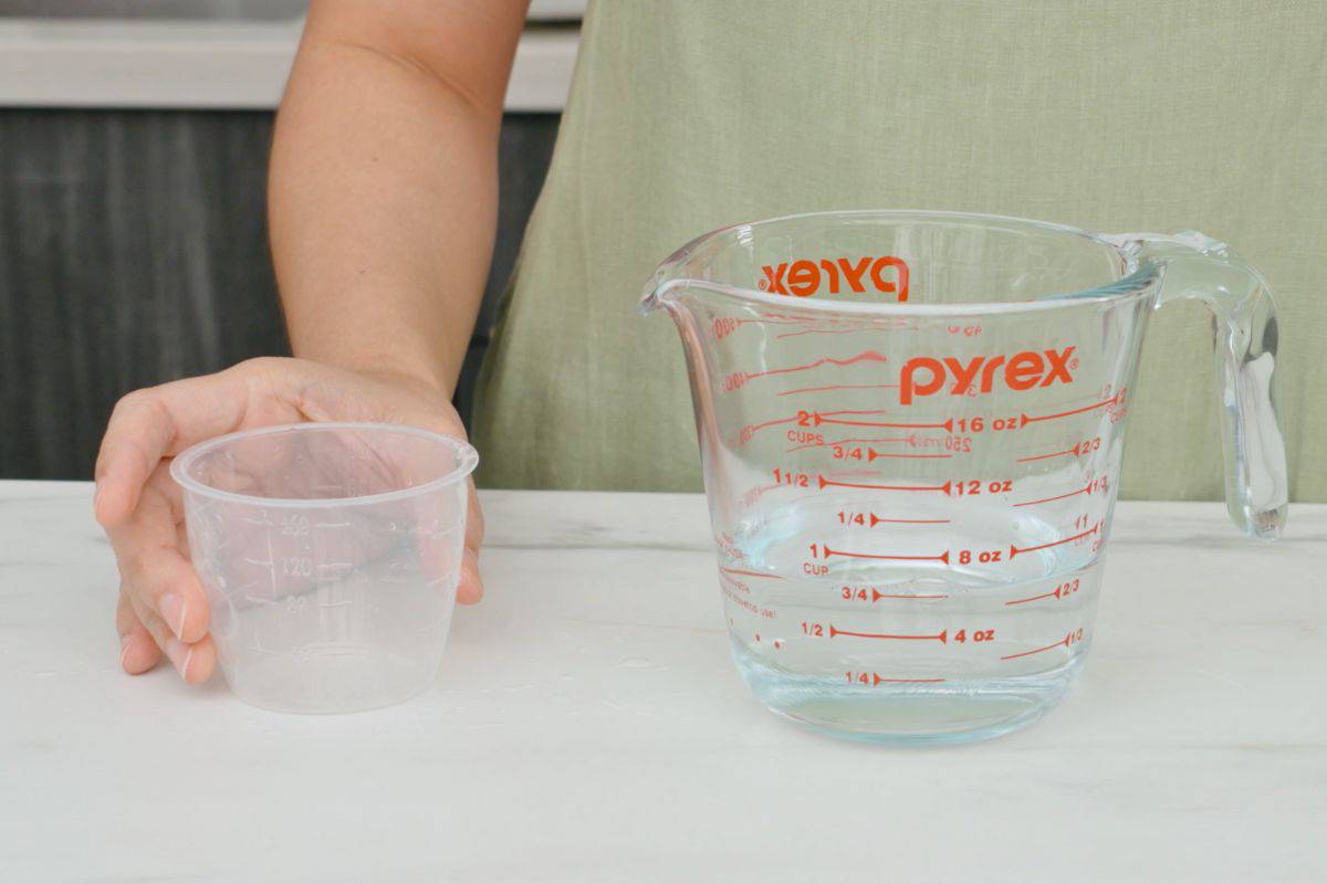 rice cup sitting next to a glass measuring cup with ¾ cup of water in it