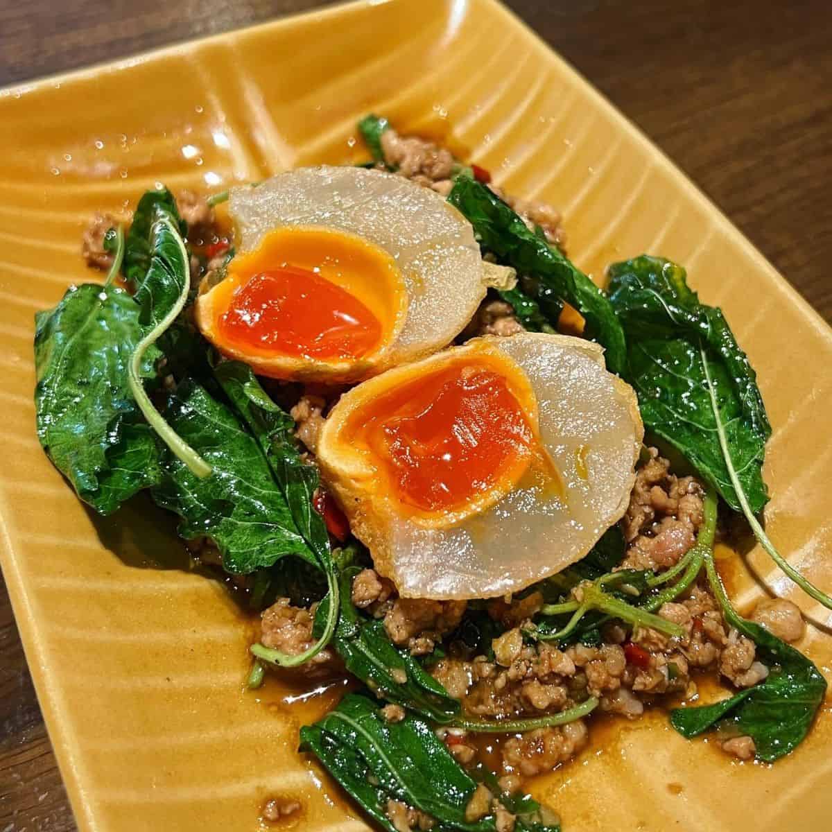 a plate of pad gaprao made with golden century eggs