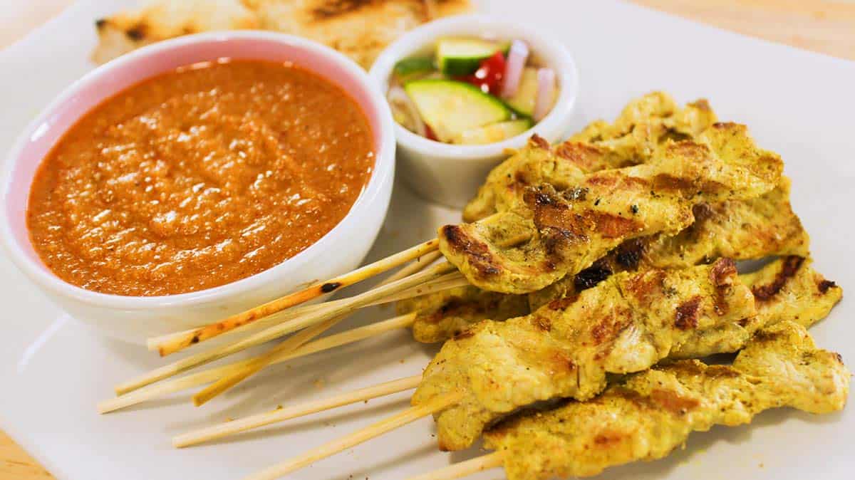 a plate of pork satay with peanut sauce